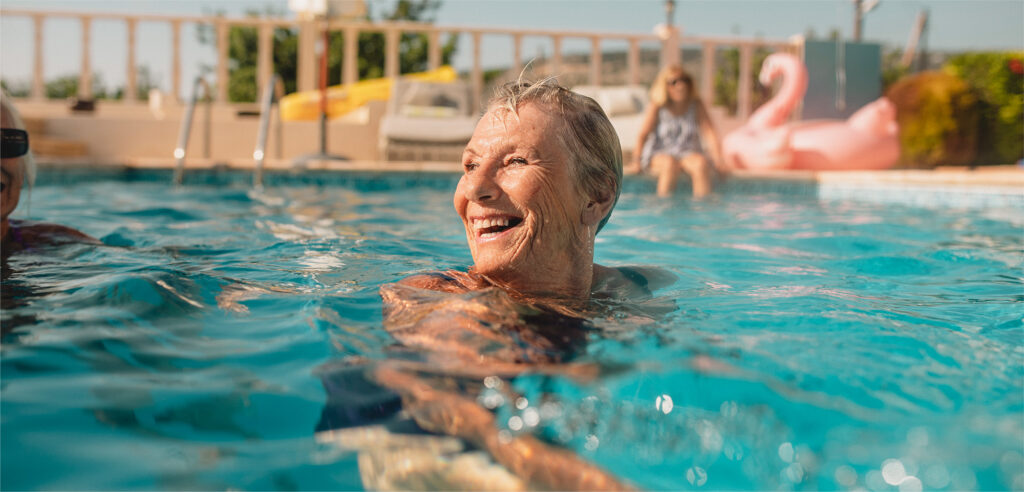 smiling elder woman in outdoor pool facing into sunshine